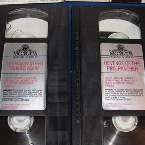 May include: Two black VHS tapes of "The Pink Panther Strikes Again" and "Revenge of the Pink Panther." Each tape has a silver label with the MGM/UA Home Video logo and movie details. The tapes are in their original cases.