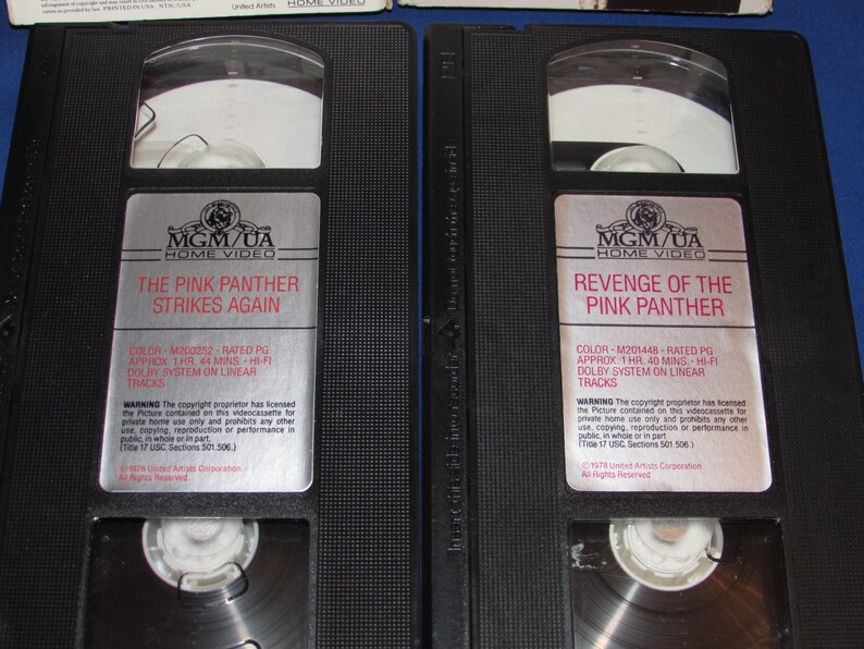 May include: Two black VHS tapes of "The Pink Panther Strikes Again" and "Revenge of the Pink Panther." Each tape has a silver label with the MGM/UA Home Video logo and movie details. The tapes are in their original cases.
