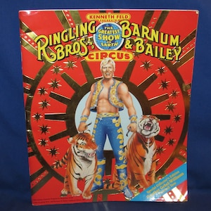 May include: A red, gold, and white program for the Ringling Bros. and Barnum & Bailey Circus. The cover features a man in a gold vest and blue pants standing with two tigers. The text on the cover reads "Ringling Bros. and Barnum & Bailey Circus, The Greatest Show on Earth".