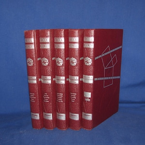 May include: A collection of five red hardcover books with silver lettering and designs. The spines display titles and volume numbers. The books are arranged together, with the fifth book showing a geometric design on its cover.