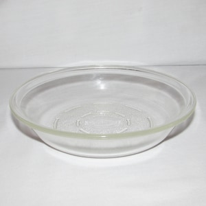 May include: A clear, round glass bowl with a slightly raised rim. The bowl has a simple, classic design, suitable for serving or display. The bowl is made of transparent glass, allowing the contents to be visible.