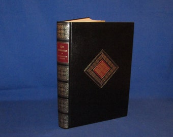 May include: A black leather-bound book with gold accents and a red and gold diamond design on the cover. The title "The Rememberer" is printed on the spine.