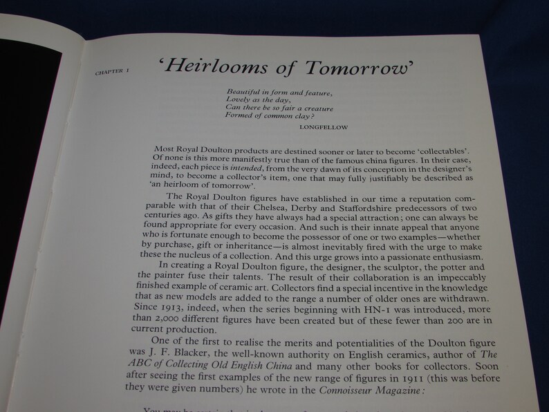 May include: A book titled 'Heirlooms of Tomorrow' with a quote from Longfellow about the beauty of objects made from common clay. The book discusses the history of Royal Doulton figures and their appeal as collectibles.