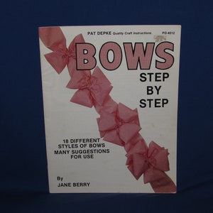 May include: A white booklet with the title "BOWS STEP BY STEP" and a red and white gingham ribbon bow design. The booklet is by Jane Berry and includes 18 different styles of bows with many suggestions for use.