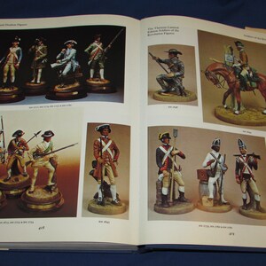 May include: A book featuring a collection of miniature figurines depicting soldiers from the American Revolutionary War. The book includes detailed images of the figurines, showcasing their intricate details and historical accuracy.