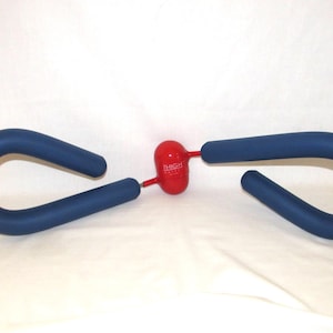 May include: A blue foam-covered thigh exercise device with a central red plastic housing. The red component features the white text THIGH TONER printed on its surface. The device consists of two curved handles connected to the central unit.