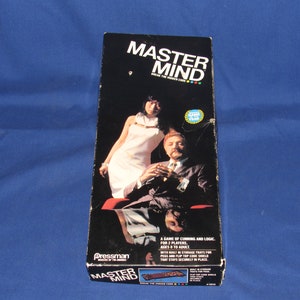 May include: A vintage board game box for Mastermind, a game of logic and deduction. The box features a black and white image of two people playing the game. The text on the box reads "Mastermind Break the Hidden Code".