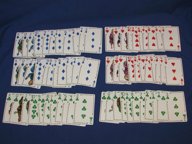 May include: Several decks of playing cards are arranged on a blue surface. The cards are organized into suits: diamonds, hearts, and clubs. Each card displays its suit symbol and number, with face cards also present.