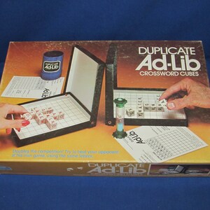 May include: A game box for Duplicate Ad-Lib Crossword Cubes. The box is orange and brown with a picture of the game board and cubes. The game is a word game where players try to create crossword puzzles using letter cubes.