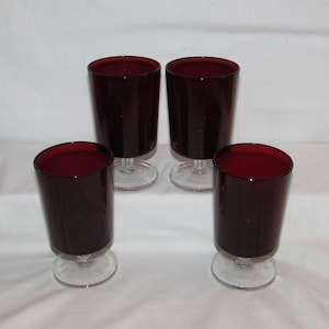 May include: Set of four ruby red glass tumblers with clear glass stems. The glasses are all the same size and shape.
