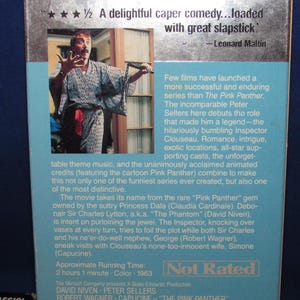 May include: VHS tape for the movie "The Pink Panther" featuring Peter Sellers. The cover has a photo of a man in a robe and text that reads "A delightful caper comedy...loaded with great slapstick."