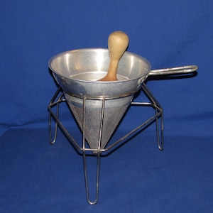 May include: A white ceramic mug with a black handle and the text "But First, Coffee" in a bold, black font. The mug is sitting on a wooden surface. The mug is approximately 4 inches tall.