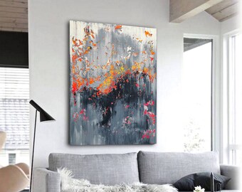 May include: Abstract painting with a gray, black, and orange color scheme. The painting is hanging on a white wall above a gray couch with a white throw blanket.