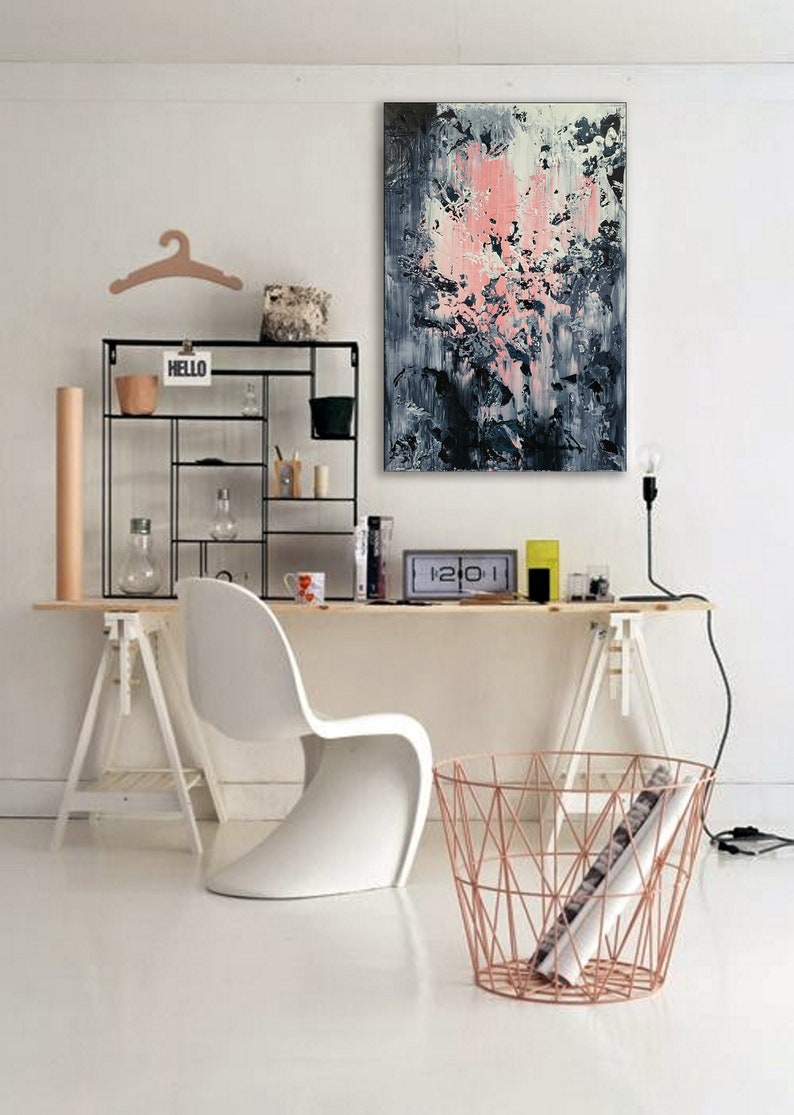 May include: A white desk with a white chair, a black metal shelf with the word "HELLO" on it, a pink and blue abstract painting, and a copper wire basket.