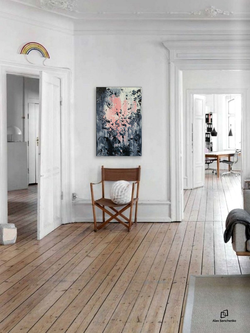 May include: Abstract painting with pink, white, and gray brushstrokes on a canvas. The painting is hanging on a white wall in a room with wooden floors.