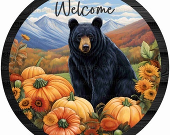 May include: Round wooden sign with a black bear, pumpkins, and sunflowers. The sign has the word "Welcome" at the top, with a mountain and fall foliage background. The sign is perfect for fall and autumn decor.