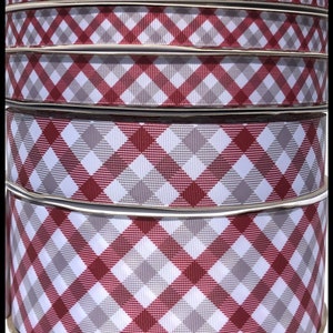 May include: Four spools of red and gray plaid ribbon. The ribbon is a gingham pattern with a white background and red and gray squares.