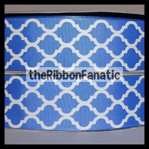 May include: Close-up of a blue ribbon with a white quatrefoil pattern. The ribbon has a textured surface and the text "theRibbonFanatic" is printed across the center. This ribbon is suitable for crafts and gift wrapping.