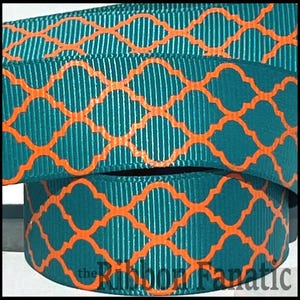 May include: Close-up of teal grosgrain ribbon with an orange quatrefoil pattern. The ribbon is folded over itself, showing the texture and design. The Ribbon Fanatic logo is visible at the bottom.