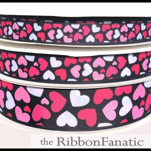 May include: Three spools of black ribbon with a white and pink heart pattern. The ribbon is on a white background. The text "the Ribbon Fanatic" is at the bottom of the image.