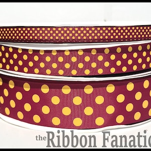 May include: Spools of decorative ribbon in burgundy and gold. The ribbons feature polka dot patterns in varying sizes. The text "the Ribbon Fanatic" is visible at the bottom. Ideal for crafting and gift wrapping.