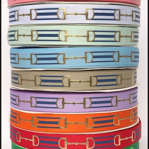 May include: A stack of 10 rolls of gold snaffle patterned ribbon in various colors, including pink, white, light green, light blue, beige, lavender, orange, red, green, and blue. The ribbon is striped with navy blue stripes. The text "the Ribbon Fanatic" is at the bottom of the image.
