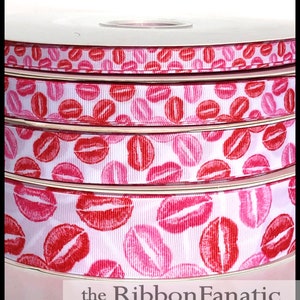 May include: A spool of white ribbon with a repeating pattern of pink and red lips. The ribbon is on a white spool with a clear plastic cover.