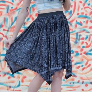 May include: A black and white patterned skirt with a asymmetrical hemline. The skirt is made of a soft, flowing fabric.