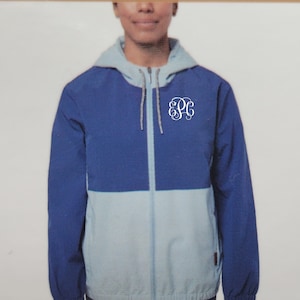 May include: A blue and light blue hooded jacket with a zipper closure. The jacket has a white monogram on the front that says "EPC".