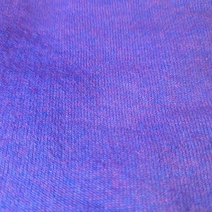 May include: Close-up of a purple and blue textured fabric. The fabric has a soft, fuzzy texture.