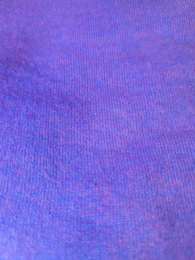 May include: Close-up of a purple and blue textured fabric. The fabric has a soft, fuzzy texture.