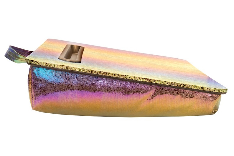 May include: A iridescent gold and purple pillow with a built-in tray. The tray is made of a light brown material and has a rectangular shape.