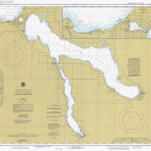 May include: A nautical chart of Lake Charlevoix in Michigan, showing the lake's depth and shoreline features. The chart is printed on a beige background with blue lines and text. The chart includes a compass rose and a scale bar.