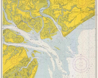 Può includere: Una carta nautica di St. Helena Sound, Carolina del Sud. La carta è stampata su uno sfondo giallo con linee blu e verdi che rappresentano le vie navigabili e le masse terrestri. La carta include rose dei venti, sondaggi di profondità e aiuti alla navigazione.