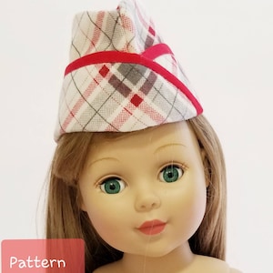 May include: A doll wearing a red and white plaid hat with a red trim. The hat has a pointed top and a curved brim. The doll has long brown hair and green eyes.