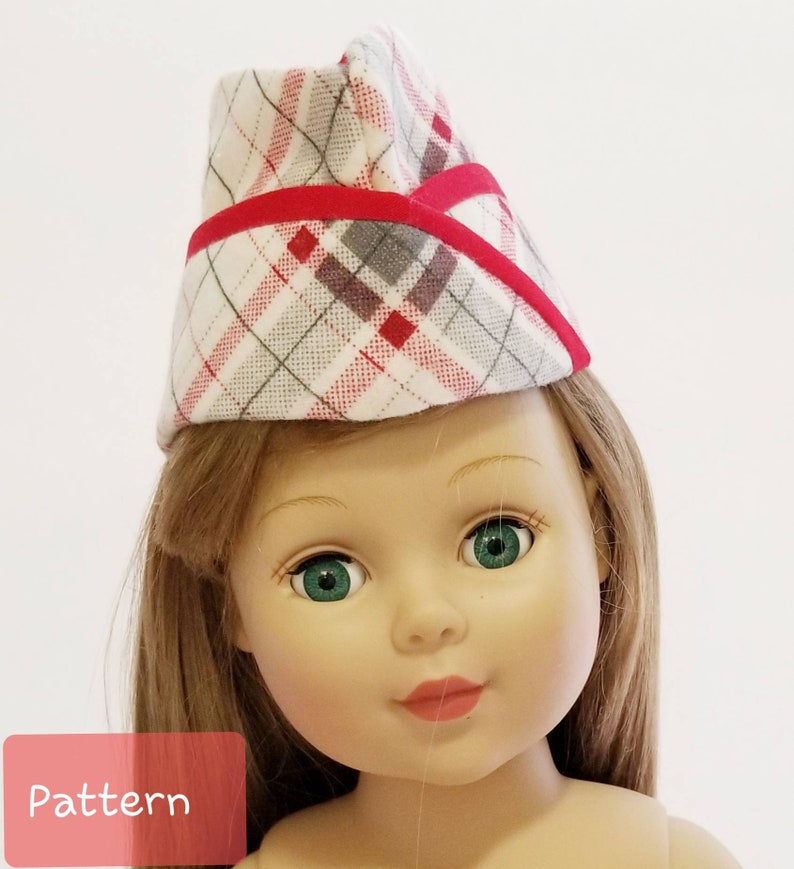 K&ouml;nnte beinhalten: Eine Puppe tr&auml;gt einen roten und wei&szlig;en karierten Hut mit rotem Besatz. Der Hut hat eine spitze Oberseite und einen gebogenen Rand. Die Puppe hat langes braunes Haar und gr&uuml;ne Augen.