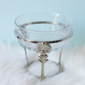 May include: A clear glass bowl with a silver rim and stand. The stand has a decorative design with a shell motif.