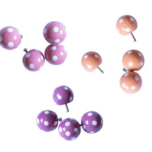 May include: Assortment of pink and orange polka dot knobs with white dots. The knobs have a screw on the back for attaching to furniture.