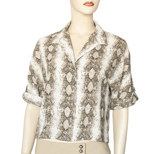 May include: A white and brown snakeskin print button-up shirt with a collared neckline and short sleeves.