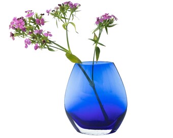 May include: A vibrant blue glass vase with a unique, rounded shape. The vase holds delicate pink flowers with green stems and leaves. The vase is empty, and the background is white.