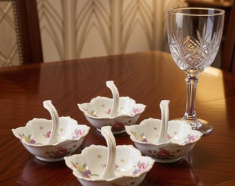 May include: Four small white porcelain bowls with curved handles, each featuring a delicate floral pattern of pink roses and yellow flowers with gold accents, accompanied by a single clear crystal stemmed glass with a cut diamond pattern.