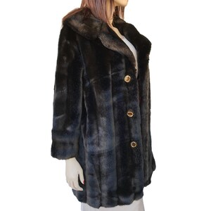 Puede incluir: Una chaqueta de piel sint&eacute;tica negra con cuello y botones dorados. La chaqueta tiene un patr&oacute;n a cuadros.