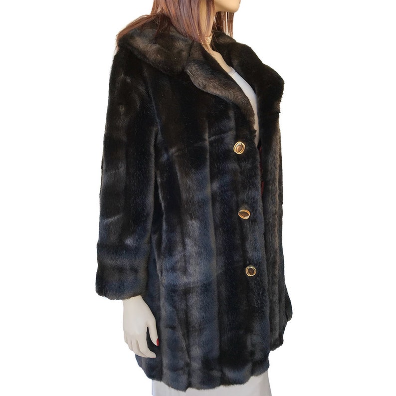 Puede incluir: Una chaqueta de piel sint&eacute;tica negra con cuello y botones dorados. La chaqueta tiene un patr&oacute;n a cuadros.