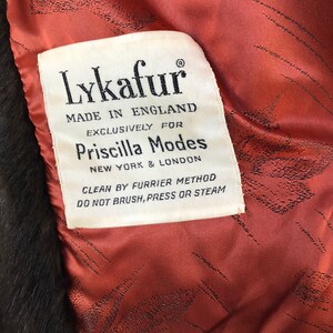 Puede incluir: Una etiqueta blanca con texto negro que dice "Lykafur Hecho en Inglaterra Exclusivamente para Priscilla Modes Nueva York & Londres Limpieza por m&eacute;todo de peletero No cepillar, presionar o vaporizar"