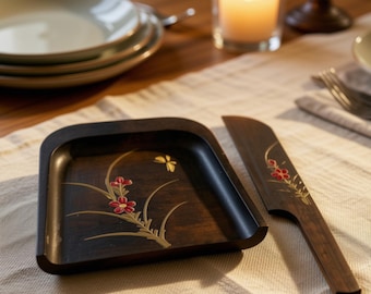 May include: A dark brown wooden square tray with rounded corners and a matching flat wooden knife. Both pieces feature a gold-toned floral design with small red petals and a gold butterfly motif painted on the dark wood surface.