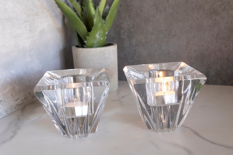 May include: Two clear glass candle holders shaped like diamonds with a tealight candle in each.