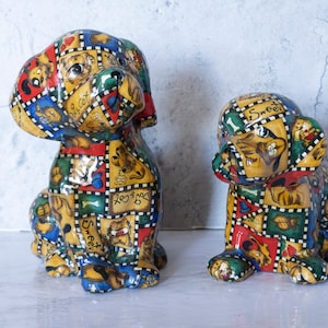 May include: Two ceramic dog figurines, one larger than the other, both with a patchwork design featuring various colors, patterns, and words like "Sweet" and "Love".
