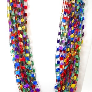 May include: A multi-strand necklace made of thin, woven strands of yarn with small, square-shaped beads in shades of red, orange, yellow, green, blue, purple, and black.
