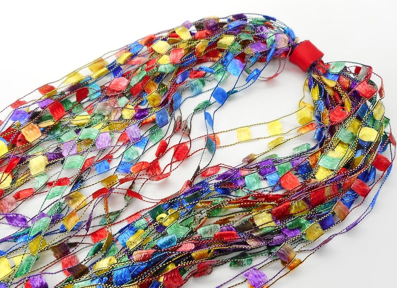 May include: A multi-coloured yarn with a variety of colours, including red, yellow, blue, green, and purple. The yarn is made of a soft, silky material and has a delicate, shimmering finish.