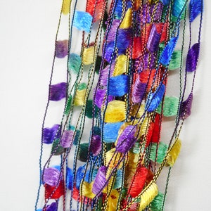 May include: A multi-coloured yarn with a fringe texture. The yarn is made up of multiple strands of different colours, including red, blue, green, yellow, and purple.